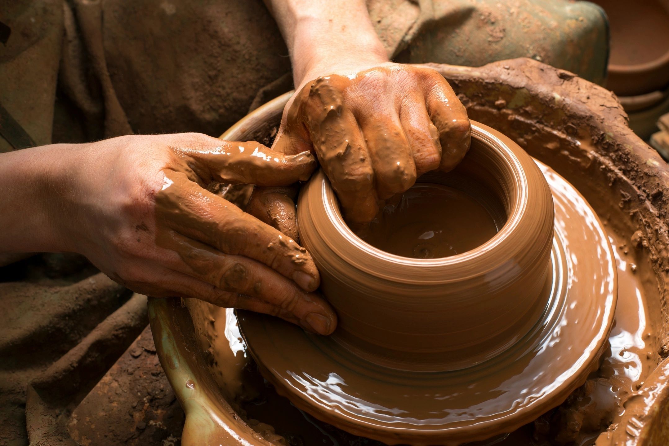 Hands throwing a clay bowl on a ceramics wheel